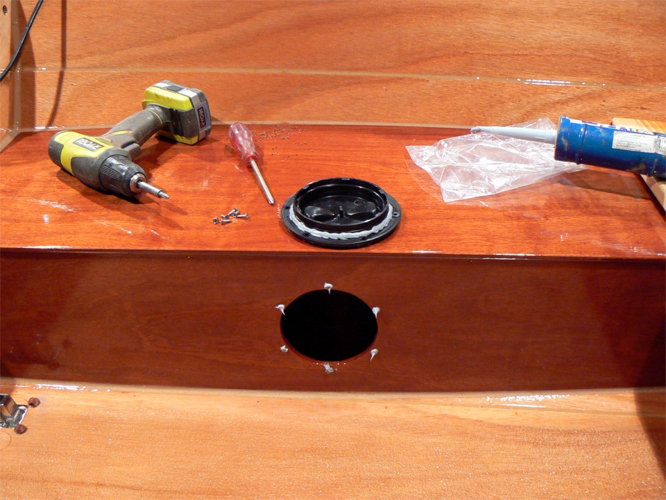 Il est temps de finir la coque : voici le montage de la trappe de l'un des caissons latéraux : j'ai déposé une goutte de mastic silicone dans chacun des trous de ses vis, et sur tout le pourtour de la trappe, il n'y a plus qu'à visser. 