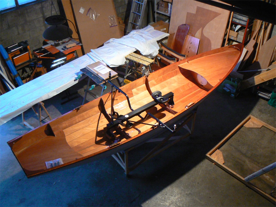Voilà le portant monté et positionné dans la Yole de Chester, que j'ai rapportée à l'atelier. J'ai déposé les planchers car je vais réaliser des sabots sur lesquels se poseront les pieds du portant à coulisse, qui sera rendu solidaire du bateau par deux boulons, passés à travers la paire de supports de dames de nage du milieu. Les sabots seront collés sur les membrures et sur les bordés de fond. Je vais également pratiquer une découpe dans le raidisseur des planchers avant et arrière afin de pouvoir monter les planchers au-dessus des sabots pour la pratique de l'aviron traditionnel, quand le portant sera démonté. 