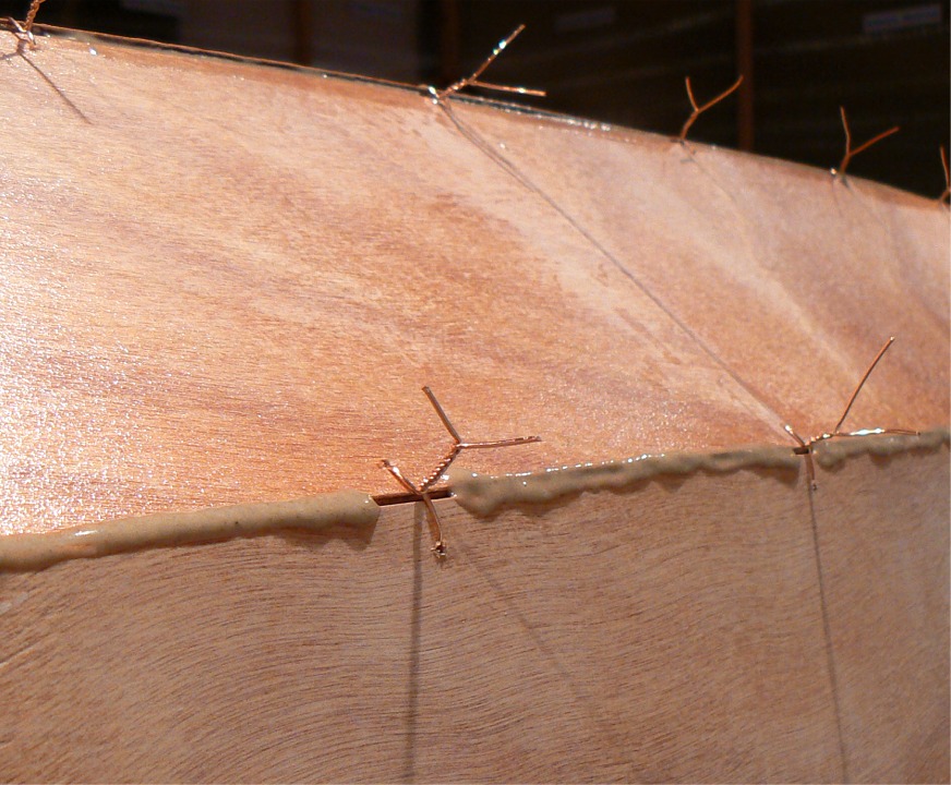 Et je passe au collage : j'ai de nouveau retourn&eacute; la coque et je d&eacute;pose un filet d'&eacute;poxy charg&eacute;e dans les joints, entre les sutures. Il vaut mieux &eacute;viter de faire tout de suites des joints continus car il sera plus difficile d'extraire les sutures prises dans l'&eacute;poxy, et surtout il y aura beaucoup plus de grattage et de pon&ccedil;age des exc&eacute;dents d'&eacute;poxy. Il vaut mieux faire un second passage sur les joints pour remplir les vides. 