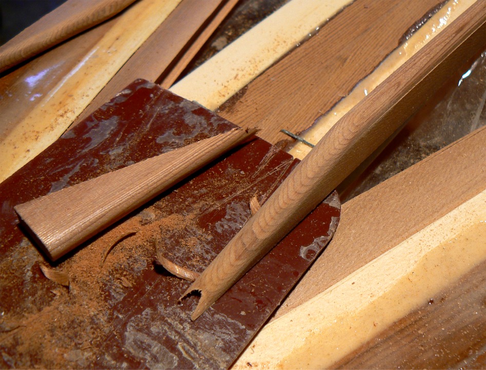 Inversement, je crée un profil convexe au bout de la latte qui va venir parallèle à la fougère : cette extrémité vient se loger dans la gorge sur le bord concave du plat-bord. J'ai sacrifié une squeegee (la plaque en plastique marron) qui me permet de faire les coupes d'extrémité à la scie "in situ" sans entailler les lattes déjà en place.