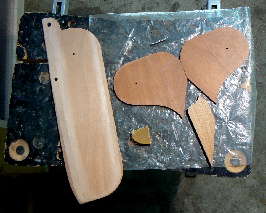 Voici les pi&egrave;ces du gouvernail : safran &agrave; gauche, et t&ecirc;te &agrave; droite, deux joues et une &acirc;me, avec une petite cale enrob&eacute;e de ruban adh&eacute;sif pour tenir l'&eacute;cartement des joues pendant le collage. Le safran est perc&eacute; de 3 trous : le petit est celui de l'axe de pivotement, celui de la pointe servira &agrave; le relever et celui du bas recevra un bout de tendeur qui le tiendra en position basse. 