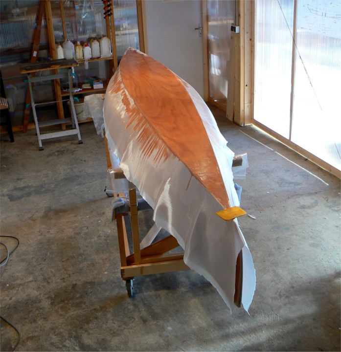 J'ai commencé par saturer le tissu sur la sole et je vais maintenant descendre sur les bordés. J'ai posé ma "squeegee" sur l'étrave pour aller mélanger une nouvelle fournée d'époxy. 