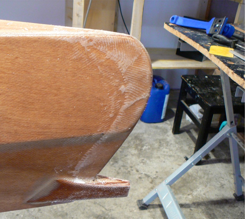 Et voilà l'étambot. Le racloir à manche bleu est visible à l'arrière-plan à droite, sur l'établi. C'est un outil méconnu car il manque de noblesse (rien que son nom...), mais quel rendement... J'ai juste dégrossi en quelques minutes afin de réduire le ponçage (inévitable) ultérieur. Harold "Dynamite Payson aime dire que la vie est trop courte pour poncer l'époxy : il a raison, elle est trop courte, mais on ne va pas quand-même pas laisser ça comme ça... 