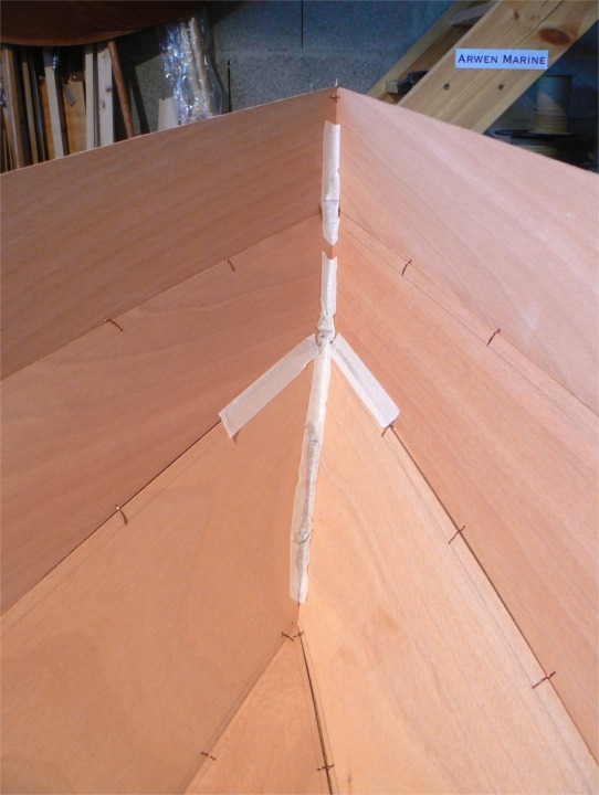 En l'absence d'Igor, un voisin m'a aidé à remettre le Skerry à l'endroit après le premier collage sur l'extérieur de la coque. Il est encore très "mou" à ce stade et je n'ose pas utiliser ma chèvre. Cette image montre l'intérieur de la poupe où j'avais collé de la bande adhésive afin d'empêcher l'époxy chargée de couler à travers les "jours" causés par la jonction imparfaite des extrémités des bordés et de maculer le bordé, que je n'ai pas encore imprégné.