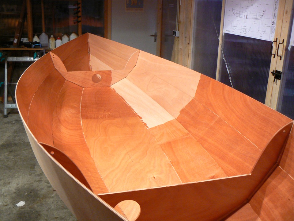 Je commence par imprégner l'ensemble de la surface intérieure. Sur cette image, il ne reste plus à couvrir que le petit coin sur bâbord arrière. La façon dont l'époxy fait "sortir" la texture du bois en le "mouillant" m'esbaudit à chaque fois ! Cette image montre que si la découpe pour la trappe du caisson étanche arrière est centrée, celle de l'avant est décalée sur tribord afin de ne pas se trouver bloquée par le mât lorsque le bateau sera gréé. 