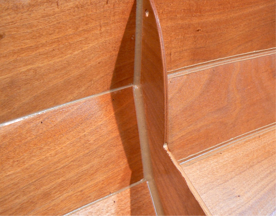 Dans la foulée, pendant que l'époxy d'imprégnation est encore "molle", je fais les joints sur l'intérieur. Il est important d'imprégner le bois avant de faire les joints, car la présence d'époxy "claire", même non durcie, évite que le bois soit taché par la charge de l'époxy des joints. Cette image montre le coté bâbord de la membrure de l'arrière : à gauche, j'ai déjà "nettoyé" les bords des joints après les avoir lissés (avec l'arme secrète, la cuiller en plastique !) A droite, j'ai fait le lissage, mais pas encore le nettoyage. 