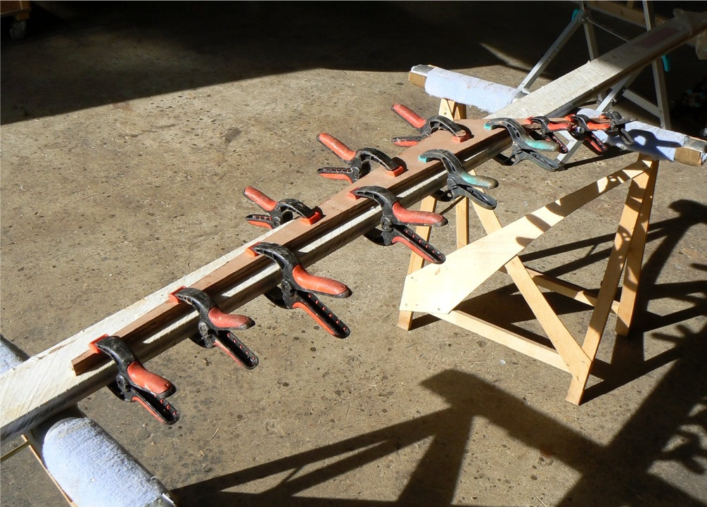 Entretemps je colle à l'époxy chargée les deux plis de l'aileron du Skerry. Je contrains une ancienne barrière de parking à un travail enfin utile : le collage est pressé dessus et elle assure que l'aileron sera rectiligne lorsque l'époxy aura durci. 