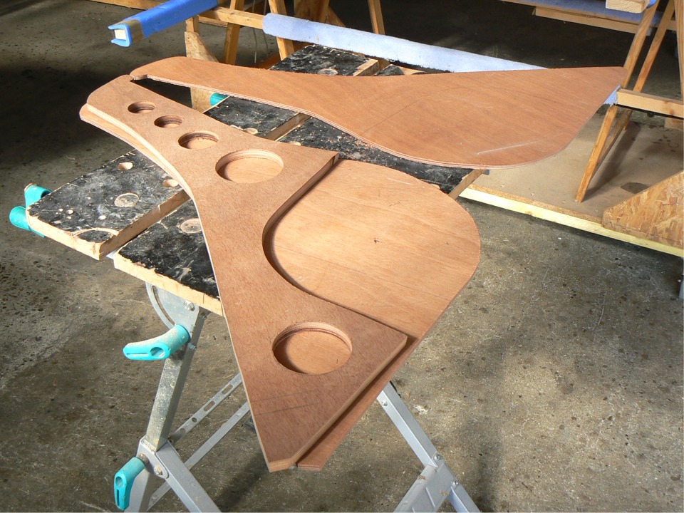 Quelques instants plus tard, j'ai coupé les trois pièces du gouvernail et le safran, que l'on ne voit pas ici, et je m'aprête à coller l'ensemble à l'époxy chargée (pas le safran, qui reste mobile : il pivotera dans la grande partie évidée en bas à droite. Les autres trous allègent un peu l'âme. 