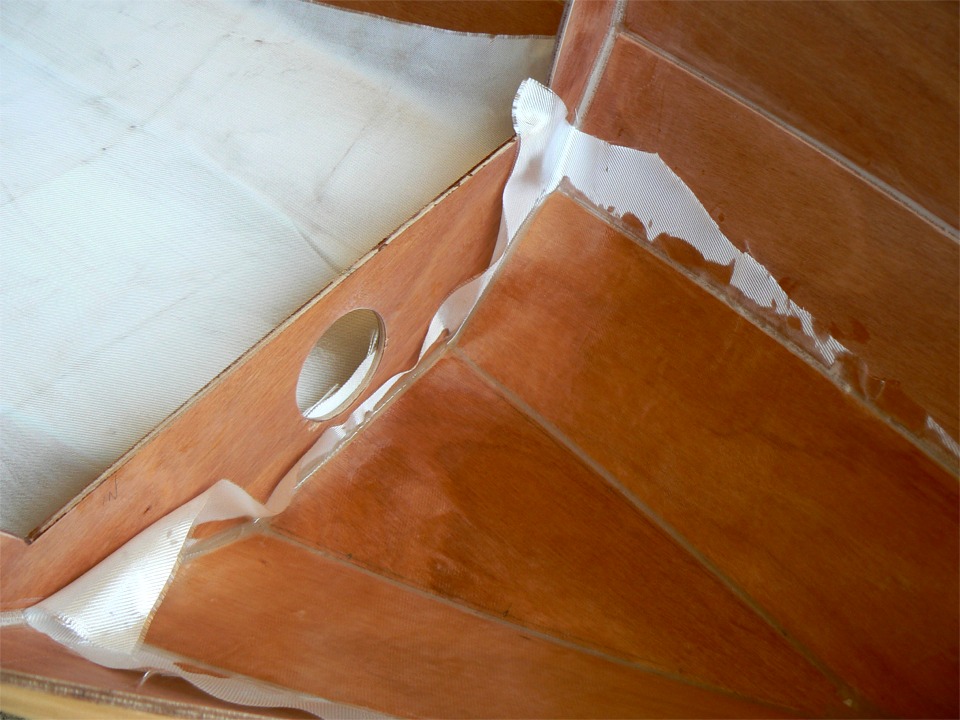 La semaine dernière, j'avais montré le début de la construction de "Numéro 33" (le Skerry que je me dépèche de construire pour participer à la Semaine du Golfe, et qui est le 33e bateau que je construis) et j'en étais arrivé à la préparation de la surface intérieure pour la stratification : nous y voila ! Vue du compartiment arrière, dans lequel je viens de saturer le tissu de verre d'époxy, alors que l'on voit qu'il est encore "sec" dans le compartiment central, à gauche sur l'image. 