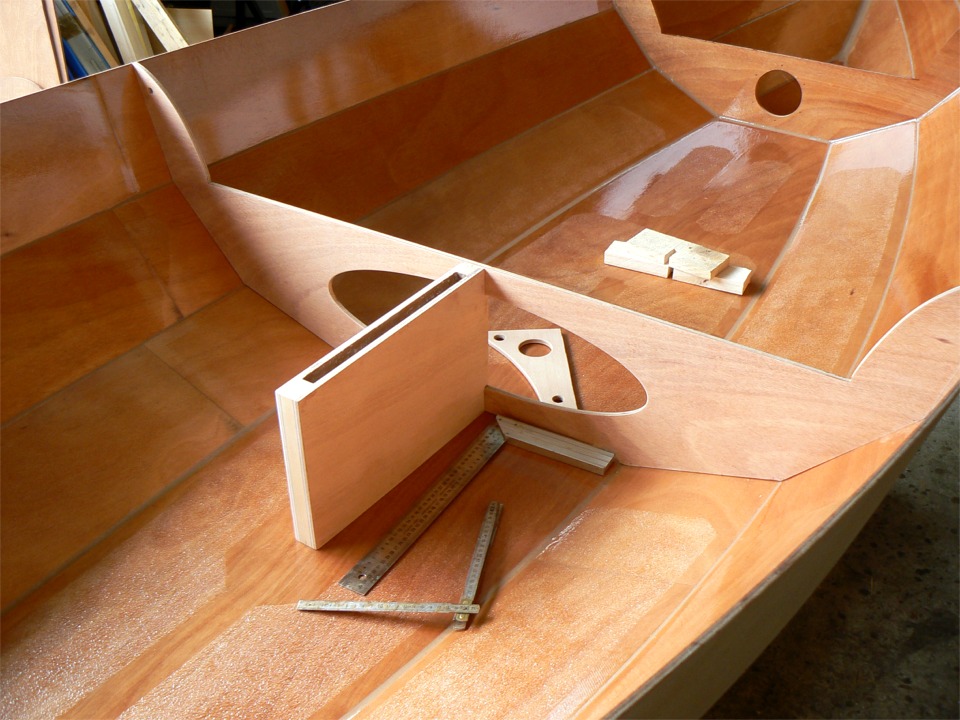 J'ai re-suturé la membrure centrale à sa place, et je viens de monter à sec (sans époxy) le puits de dérive, qui ne tient actuellement que par trois vis. On aperçoit derrière la membrure centrale une équerre que je vais fixer sur l'arrière de la membrure. Son rôle est de supporter le coté arrière du banc et surtout de reprendre la traction de l'écoute qui est normalement fixée sur une patte d'oie à travers l'arrière du banc. Je préfère ajouter cette équerre pour pouvoir border à fond sans arrière-pensée au près. 