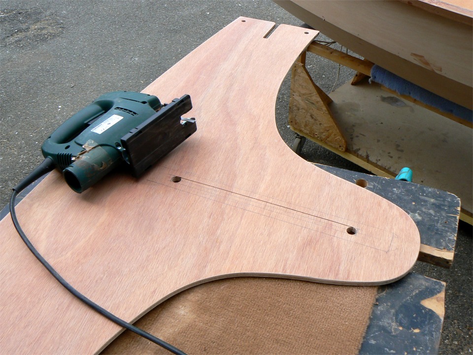 Avant de coller le banc central, je pré-découpe l'ouverture haute du puits de dérive. J'ai percé un trou à chaque bout en 14 mm et je les relie à la scie sauteuse. J'élargirai l'ouverture à la défonceuse (mon outil préféré) pour atteindre les 18 mm de largeur du puits après durcissement du collage. 