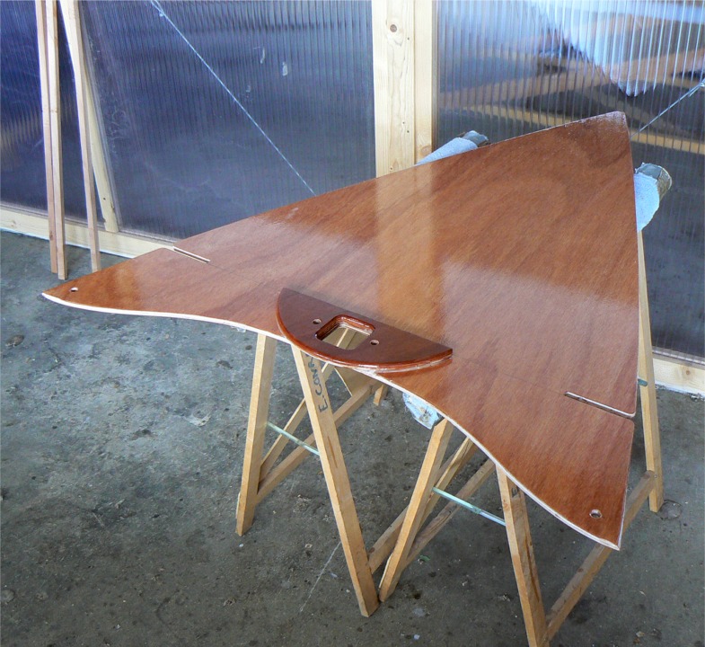 En prélude au collage des dessus de caissons et du banc central, je repasse une couche d'époxy sur leur face inférieure, comme sur les parois des caissons avant et arrière. J'ai remplacé le renfort standard d'étambrai par cette pièce en demi-lune, réalisée en contreplaqué makoré de 12 mm. 