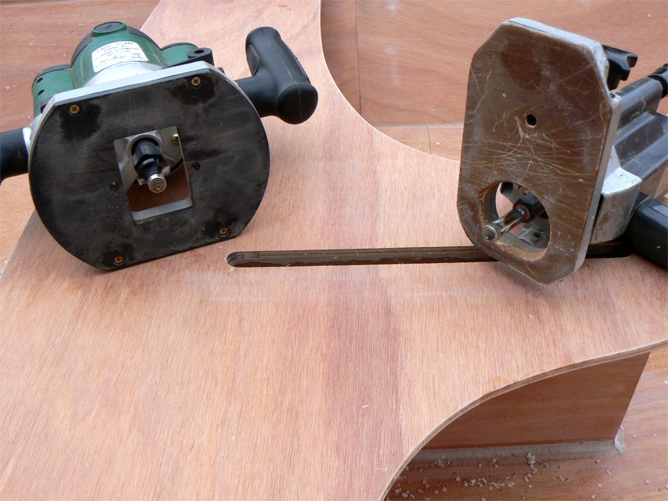 Dialogue de défonceuses : à droite, la fraise droite, à gauche la fraise en quart de rond, toutes deux sont équipées d'un guide, le petit roulement en bas des fraises (c'est la saison), qui doit tourner à plus de 20.000 tours/minute. Je passe d'abord avec la fraise droite pour élargir l'ouverture du puits de dérive à la largeur interne de celui-ci, car le guide arrête la coupe quand il prend appui sur la face interieure du puits. La photo est prise à l'issue de cette première opération. Je vais ensuite passer avec la fraise en quart de rond pour "casser" l'angle droit sur l'ouverture du puits. 