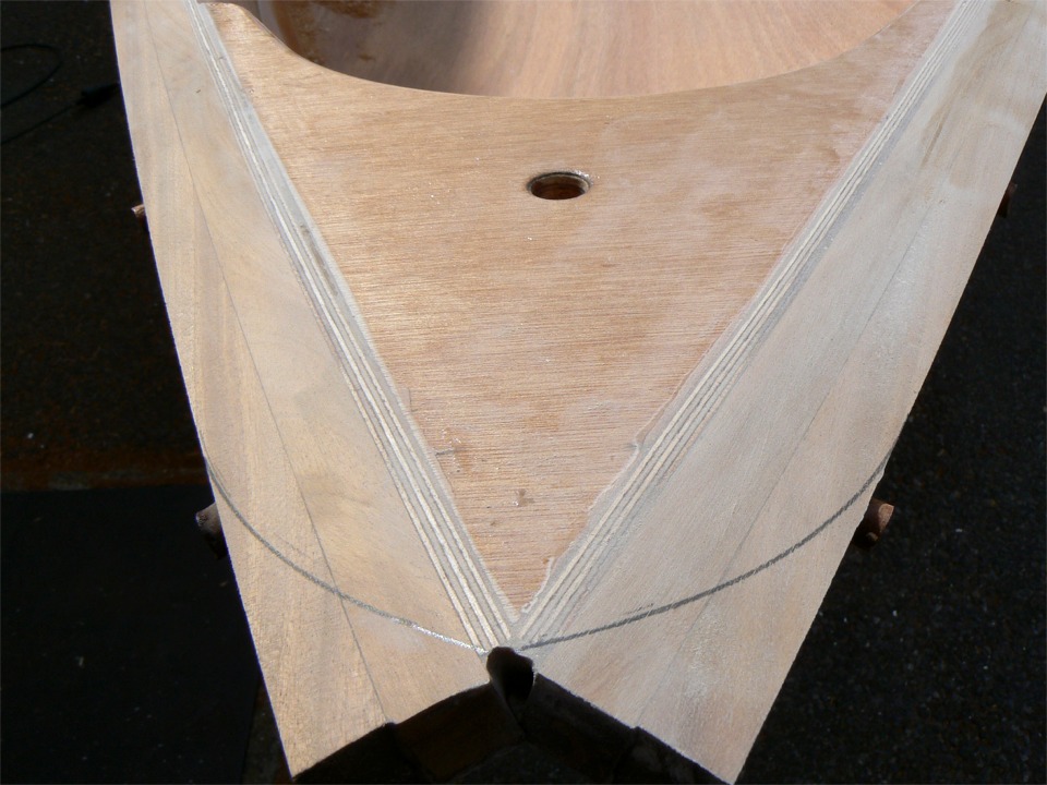 Je viens d'araser la face supérieure des listons au rabot, et je dois encore faire la finition à la ponceuse à bande (on voit qu'il reste de l'époxy sur l'avant bâbord de la guirlande). Mais d'abord je vais couper leur extrémité avant et arrière (ici c'est l'avant) en arc de cercle à la scie sauteuse. Les petits boutons que l'on aperçoit sur l'extérieur des listons sont les "tapons" qui obturent les trous des vis inox qui tiennent les extrémités des listons. Je ne peux pas couper plus ici, sinon je tombe sur la vis. 