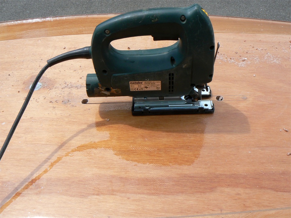 Apr&egrave;s avoir trac&eacute; entre les deux rep&egrave;res fournis par les vis de fixation du puits (les taches sombres que l'on aper&ccedil;oit &agrave; gauche et &agrave; droite du trac&eacute;), puis perc&eacute; deux trous de 14 mm (pour un puits d'une largeur th&eacute;orique de 20 mm) , je relie les trous &agrave; la scie sauteuse. 