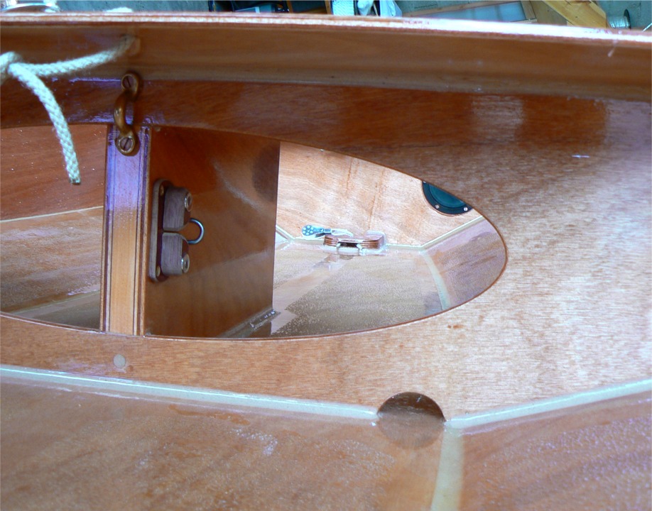 Voici le taquet coinceur en Celoron (toile bak&eacute;lis&eacute;e) fix&eacute; sur la joue tribord du puits de d&eacute;rive. le pontet en laiton sert &agrave; guider le tendeur qui court sous le banc central de bord &agrave; bord, et qui permet de coincer le bout des avirons lorsque l'on fait de la voile (le tendeur n'est pas encore en place). 
