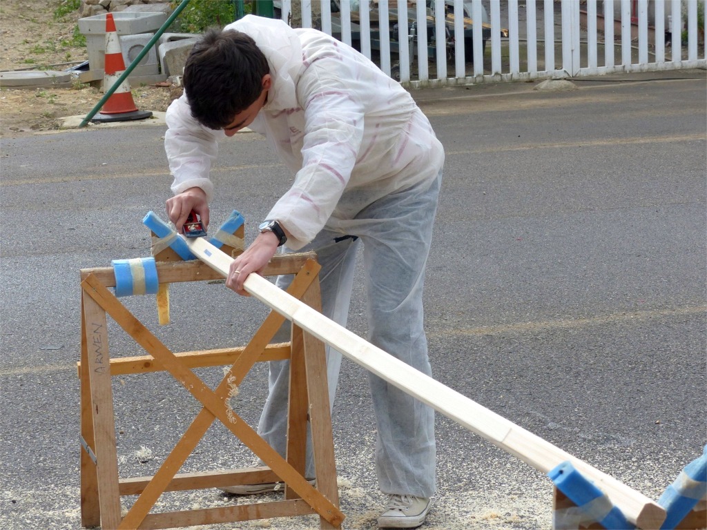 Thibault utilise le petit rabot à main pour arrondir les arêtes de la bôme et de la vergue. 