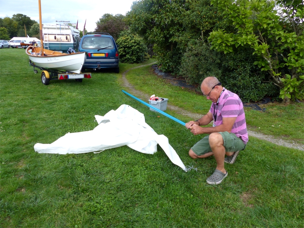 Nous retrouvons sur place Gérard et La Marie Pupuce. Gérard a un gros souci car il a oublié sa vergue à la maison. Heureusement, le responsable du club de voile de Nort-sur-Erdre lui donne un vieux mât de planche à voile, et nous voyons ici Gérard occupé à transformer ce mât en vergue (car bien sur, Gérard McGyver a toujours une scie et une perceuse dans son paquetage...) 