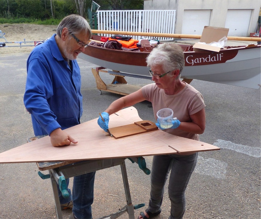 Nous avons ouvert le passage du m&acirc;t &agrave; travers le si&egrave;ge avant et les deux couches de renfort de l'&eacute;tambrai, et Ma&iuml;t&eacute; passe une couche d'&eacute;poxy sur le renfort : toute la surface du contreplaqu&eacute; re&ccedil;oit au minimum deux couches d'&eacute;poxy afin de le renforcer et le prot&eacute;ger de l'humidit&eacute;. 
