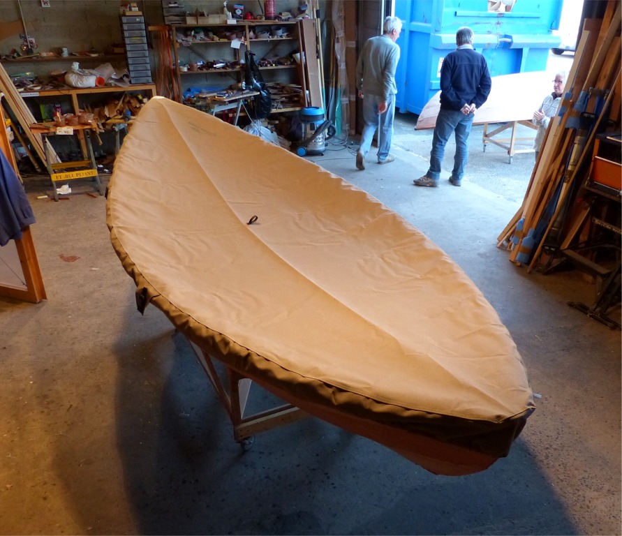 Ce taud est r&eacute;alis&eacute; en tissu acrylique teint&eacute; dans la masse et "respirant". Il est &eacute;quip&eacute; d'un tendeur sous gaine sur toute sa p&eacute;riph&eacute;rie et de deux sangles &agrave; boucle au tiers avant et arri&egrave;re de la coque. Pour &eacute;viter l'accumulation de l'eau de pluie, il faudra mettre au point une structure minimale pour tendre le dessus en l&eacute;ger d&ocirc;me convexe, au lieu du concave visible ici, en l'absence de support. 