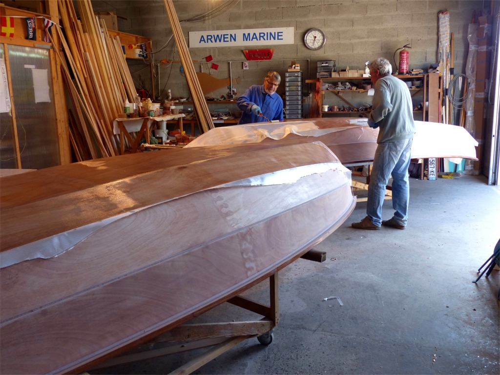Nous travaillons &agrave; l'int&eacute;rieur malgr&eacute; le beau temps, car il faut &eacute;viter que la stratification fra&icirc;che soit expos&eacute;e au soleil ou &agrave; une &eacute;l&eacute;vation de temp&eacute;rature qui causerait la formation de bulles caus&eacute;es par le "d&eacute;gazage" du contreplaqu&eacute; (&eacute;mission de vapeur d'eau du fait de la chaleur). En effet le contreplaqu&eacute; "sec" contient autour de 10% d'humidit&eacute;, ce taux variant en fonction de la temp&eacute;rature et de l'humidit&eacute; ambiante, tant que des &eacute;changes sont possibles avec l'ext&eacute;rieur. L'impr&eacute;gnation &agrave; la r&eacute;sine &eacute;poxy et la stratification vont bloquer ces &eacute;changes. 