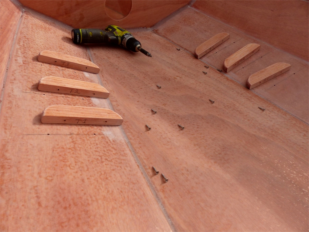 Je pr&eacute;pare aussi le collage des 3 paires de cale-pieds. On voit ici que je les ai marqu&eacute;s apr&egrave;s le premier montage "&agrave; sec" (sans &eacute;poxy) : en principe, tous les cale-pieds sont interchangeables, mais il peut y avoir une petite d&eacute;viation sur l'&eacute;cartement des deux trous de vis, et il est donc plus facile de remonter d&eacute;finitivement chacun &agrave; l'emplacement o&ugrave; il a &eacute;t&eacute; mont&eacute; une premi&egrave;re fois. Pour ceux qui aiment la pr&eacute;cision, ils sont marqu&eacute;s "T1" &agrave; "T3" sur tribord, et "B1" &agrave; "B3" sur b&acirc;bord. 