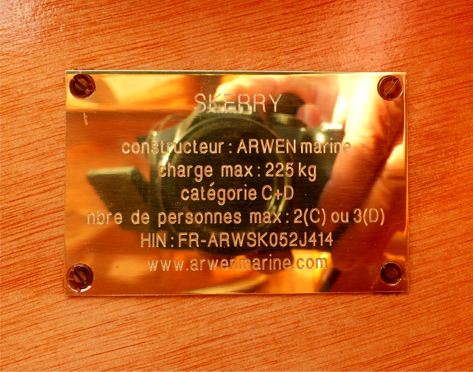 Gros plan sur la plaque de constructeur, qui refl&egrave;te l'appareil photo et les gros doigts de l'op&eacute;rateur, qui n'est manifestement pas un schtroumpf (m'enfin, un schtroumpf aurait seulement quatre doigts !) 