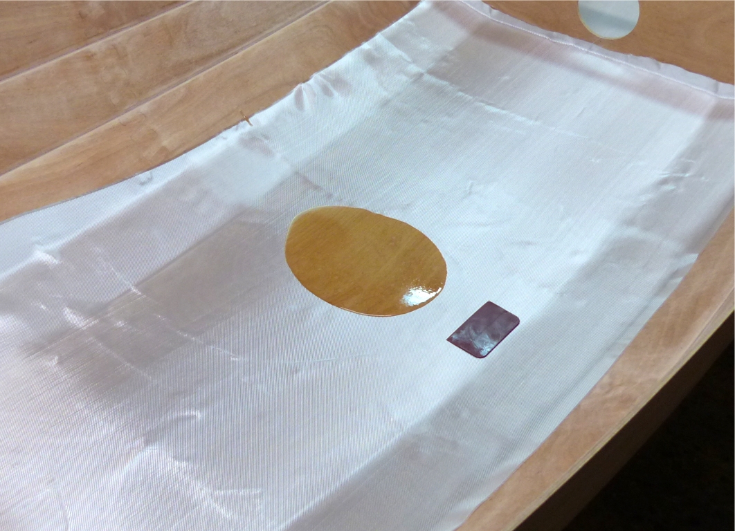 Je drape trois pi&egrave;ces de tissu de verre sur la surface int&eacute;rieure basse de la coque. En effet, la stratification est volontairement limit&eacute;e &agrave; la sole et aux bord&eacute;s 1, car cela suffit &agrave; rigidifier la coque et &agrave; prot&eacute;ger la surface int&eacute;rieure dans la zone o&ugrave; elle sera pi&eacute;tin&eacute;e. Le surpoids d'une stratification int&eacute;grale serait peu justifi&eacute;. De plus, les tissus les plus courants sont disponibles en largeur d'un m&egrave;tre, ce qui convient &agrave; la zone vis&eacute;e. Il n'y a qu'&agrave; l'avant que je couvre aussi les bord&eacute;s 2 afin de rigidifier un peu plus la proue. 