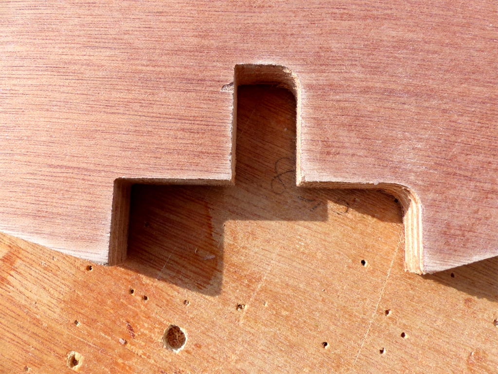 J'ai ensuite red&eacute;mont&eacute; tous les couples pour poncer leur surface (les puristes diraient &eacute;grener) et j'ai sorti ciseau, r&acirc;pe et lime pour faire les angles droits que la machine de d&eacute;coupe num&eacute;rique n'avait pas faits. En effet, la d&eacute;coupe est faite par une fraise, qui est donc incapable de couper des angles vraiment droits (il restera toujours le rayon de la fraise au fond de l'angle). Sur cette image, j'ai fait les angles de gauche et pas encore ceux de droite. L'encoche horizontale en bas est celle de la quille, et l'encoche verticale au-dessus recevra l'extr&eacute;mit&eacute; de la cloison axiale qui reprend la pression du m&acirc;t dans le r&eacute;servoir de ballast liquide.