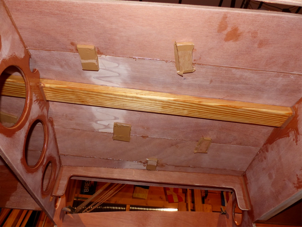 Cette photo de l'int&eacute;rieur du bordage montre ce qui remplace les sutures : ces cales sont tenues par une ou deux vis traversantes sur le bord des virures pour am&eacute;liorer la contigu&iuml;t&eacute; de leurs surfaces respectives. Ces cales de contreplaqu&eacute; (enfin un usage pour mes pr&eacute;cieuses chutes !) sont enrob&eacute;es de bande adh&eacute;sive d'emballage afin de ne pas trop coller. Je les d&eacute;monterai d&egrave;s que l'&eacute;poxy du collage entre les virures aura durci. Il ne me restera plus qu'&agrave; boucher tous ces trous de vis, tout comme on bouche les trous des sutures apr&egrave;s les avoir extraites. 