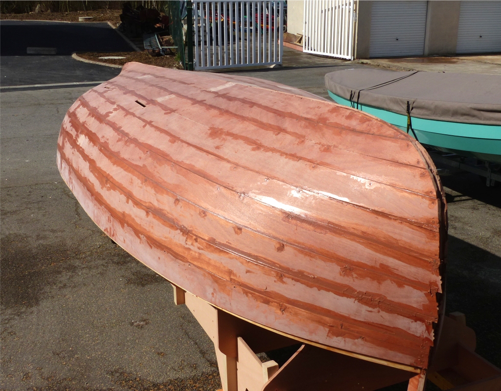 Comme je l'ai déjà dit, les virures sont collées les unes aux autres sur chant et collées sur la structure à l'époxy : quille, étrave, étambot et couples. Chaque point de contact avec la structure est également pouvu de vis inox (20 ou 30 mm de longueur en fonction des endroits). Les trous bouchés le long des "coutures" (les joints entre les virures), autres que ceux des fixations sur les couples, m'ont servi à "tirer" des cales de contreplaqué (enrobé d'adhésif d'emballage pour éviter qu'elles collent sur l'intérieur des joints), où elles ont servi à améliorer la contiguïté de surface (je sais que ce n'est ni élégant ni très clair mais je ne sais comment le dire autrement).