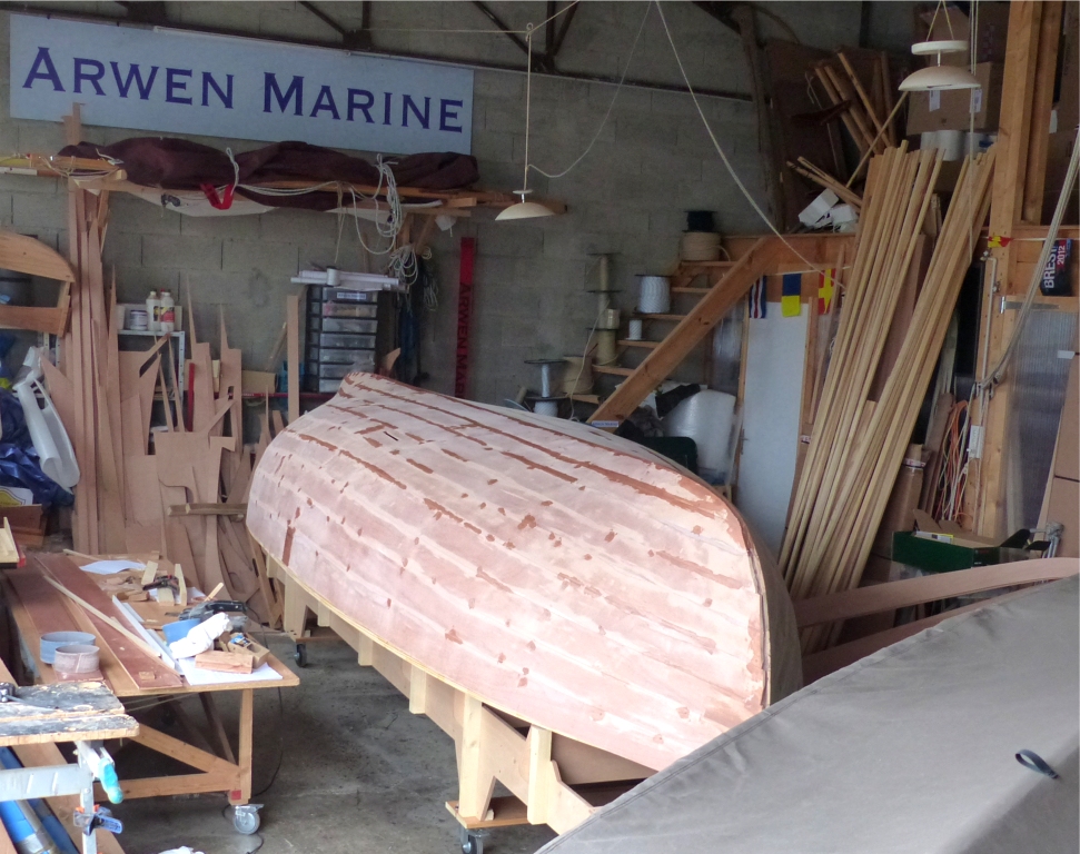 Voici une vue de la coque dimanche dernier. Le tissu marron au premier plan (le fabricant du tissu appelle cette couleur "taupe") est le taud du Silmaril, rentr&eacute; pour la nuit. Les traces "mouill&eacute;es" sur la barquette sont les derni&egrave;res retouches d'&eacute;poxy charg&eacute;e, que je m'appr&ecirc;te &agrave; poncer. 