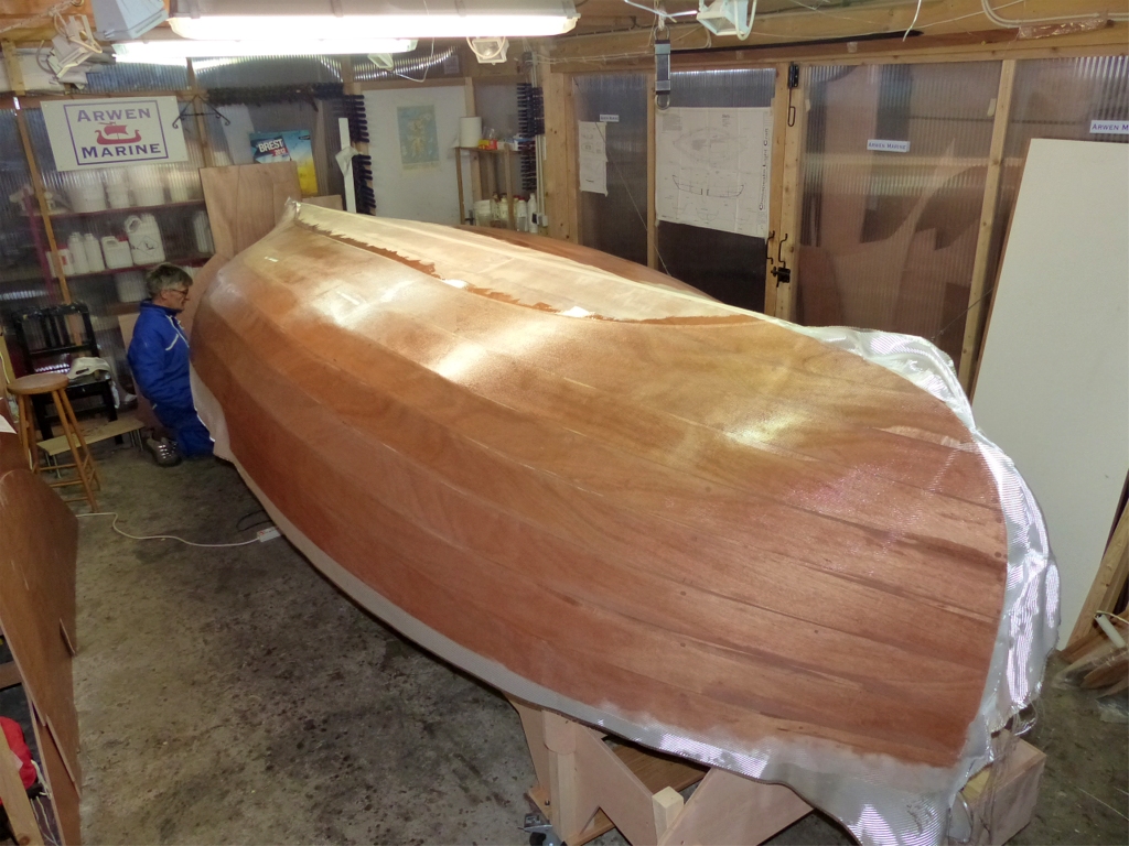 On aper&ccedil;oit Pierre tout &agrave; l'avant, presque cach&eacute; par la coque. Nous avons commenc&eacute; par poser un l&eacute; de tissu de verre en haut de chaque bord, puis avons "ferm&eacute;" sur la zone centrale avec deux l&eacute;s superpos&eacute;s sur la ligne de quille, avec un recouvrement de 30 cm au bau maximum et int&eacute;gral aux extr&eacute;mit&eacute;s. 