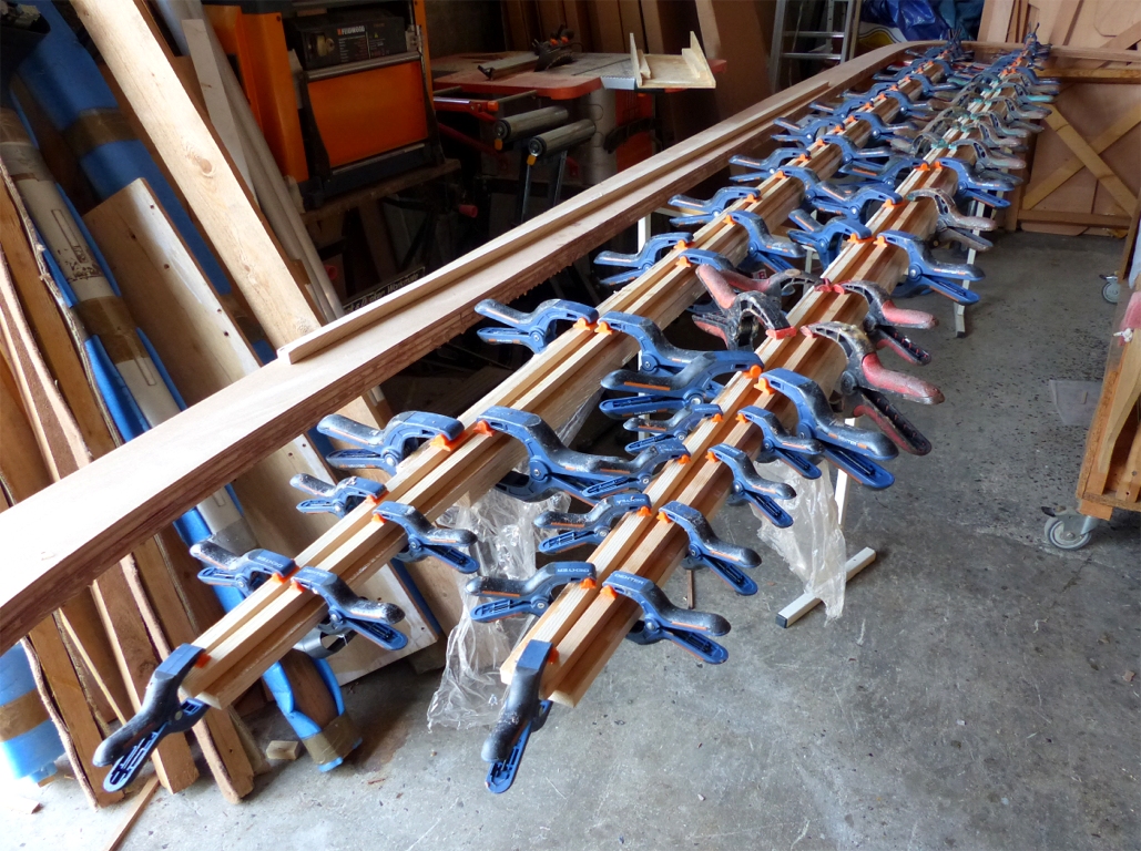 On voit ici le collage des lattes sur les deux faces principales du m&acirc;t du Skerry Raid, qui fera 4.40 m de hauteur. J'allais &eacute;crire longueur, mais cela me rappelle une anectode sur la diff&eacute;rence entre les ouvriers et les ing&eacute;nieurs. Un groupe d'ing&eacute;nieurs voulant mesurer la hauteur d'un m&acirc;t tente chacun &agrave; son tour de grimper en haut de celui-ci afin de positionner l'extr&eacute;mit&eacute; d'un d&eacute;cam&egrave;tre-ruban. Le m&acirc;t est fin et glissant, et chacun &eacute;choue dans ses tentatives. Un ouvrier qui les observait depuis un moment arrive, d&eacute;plante le m&acirc;t, le couche &agrave; terre, et fait la mesure. Il la leur donne, replante le m&acirc;t et va son chemin. Les ing&eacute;nieurs secouent la t&ecirc;te et disent : "Ce n'est pas la longueur que l'on veut mesurer, mais la hauteur"... 