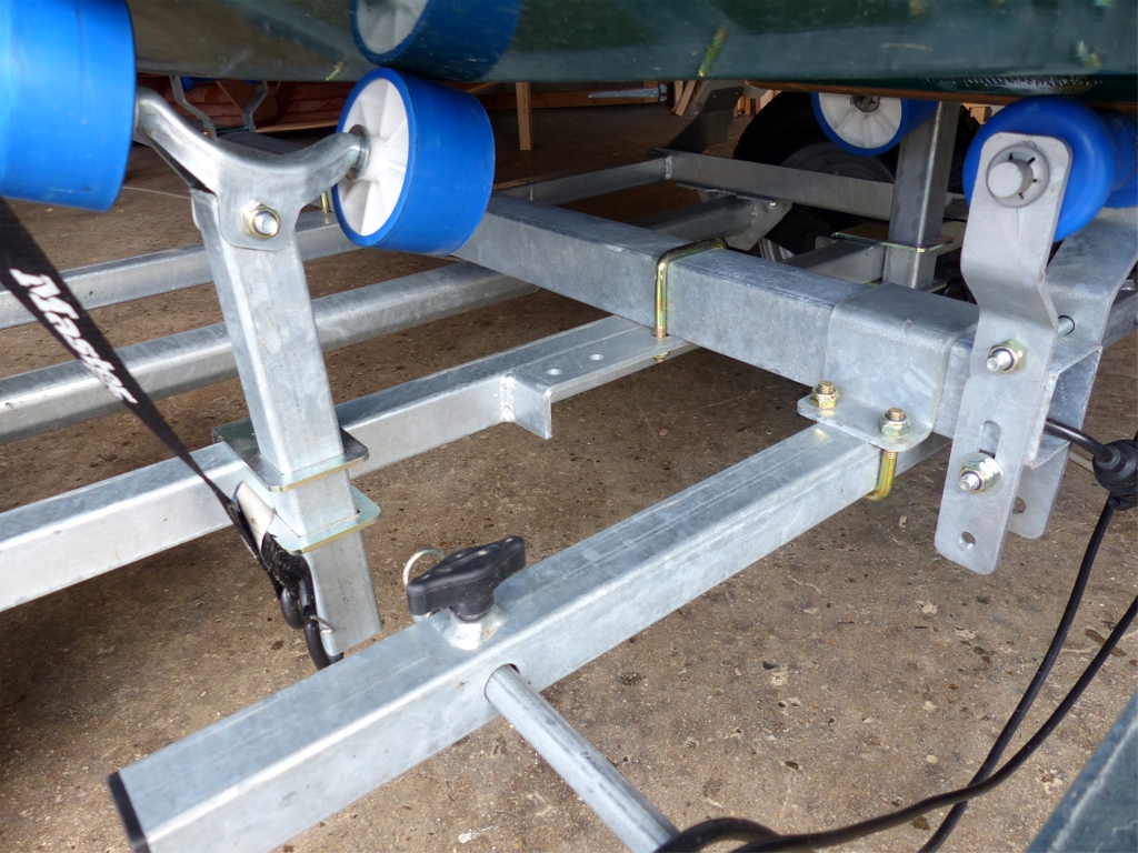 La remorque est pourvue de trois galets (&agrave; droite) r&eacute;glables sur deux hauteurs de bonlonnage sur le timon, plus possibilit&eacute; de variation en les inclinant, et de deux chandelles &agrave; positionner sur les traverses, r&eacute;glables en largeur et hauteur. Le porte-plaque avec les feux de route est amovible pour la mise &agrave; l'eau et r&eacute;glable en profondeur : on voit l'une de ses deux vis de blocage au premier plan. Une goupille s&eacute;curise chacune des deux fixations qui ont tendance &agrave; se desserrer avec les vibrations de roulement (ma seule critique sur cette remorque). 