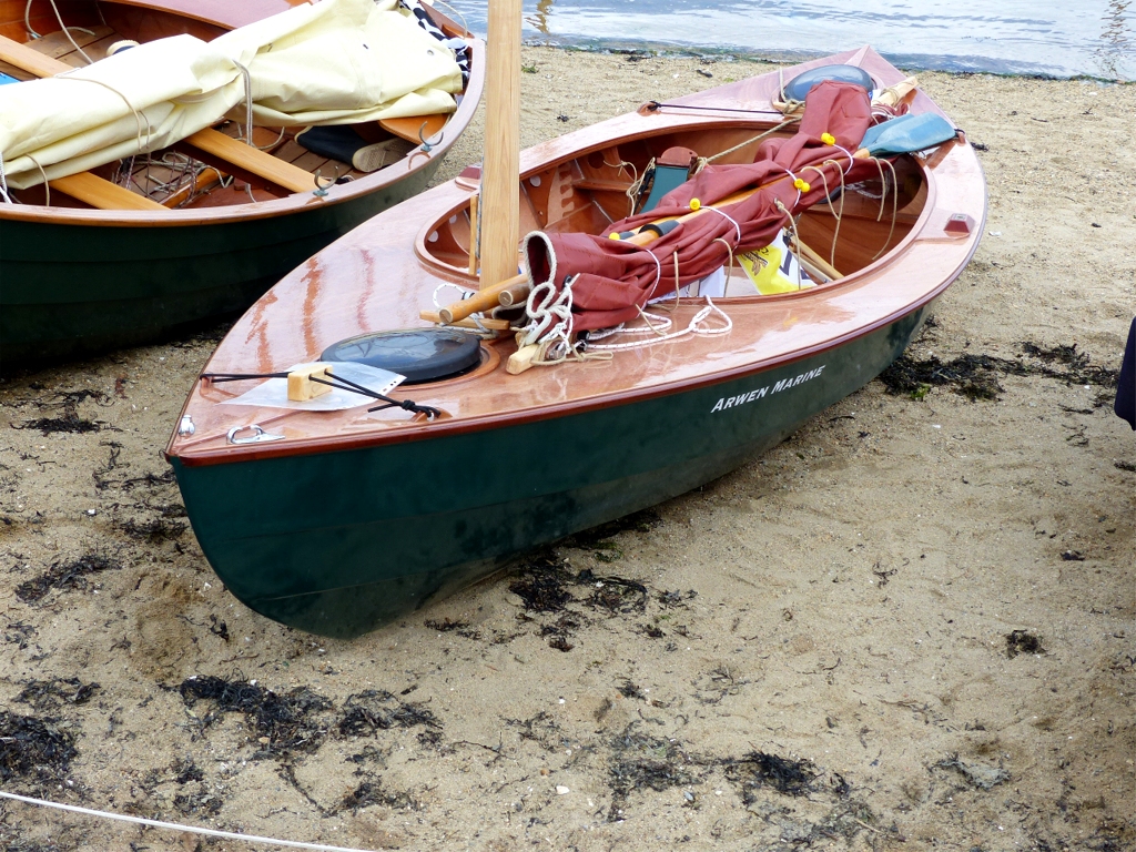 On voit clairement sur cette image comment le parall&eacute;l&eacute;pip&egrave;de en pin tenu par le tendeur en double &agrave; la proue soul&egrave;ve le tendeur afin de me permettre d'enfiler la poign&eacute;e des avirons dessous pour les ranger lorsque je navigue &agrave; la voile. Ici, il sert aussi &agrave; tenir la pochette pour &eacute;viter qu'elle s'envole. 
