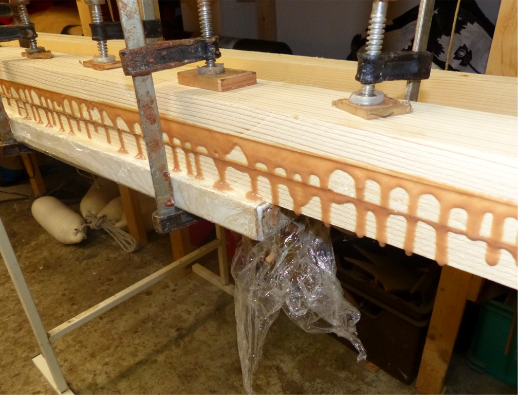 En parall&egrave;le, je colle deux m&acirc;ts de 3.80 m constitu&eacute;s de trois &eacute;paisseurs de sapin du nord. J'ai ensuite pes&eacute; ces m&acirc;ts : 7 kg avant de les affiner et de les arrondir, je pense gagner 2 kg, je v&eacute;rifierai le moment venu. En attendant, notez comme la colle (&eacute;poxy l&eacute;g&egrave;rement charg&eacute;e) coule bien des joints ! Un bon collage ne doit jamais &ecirc;tre "affam&eacute;", et je passe une bonne couche de colle en miroir sur chacune des deux faces de chaque collage. Je pense que 50% de la colle est chass&eacute;e du joint pendant le pressage : &ccedil;a fait de la perte, mais je suis s&ucirc;r de mes collages ! 