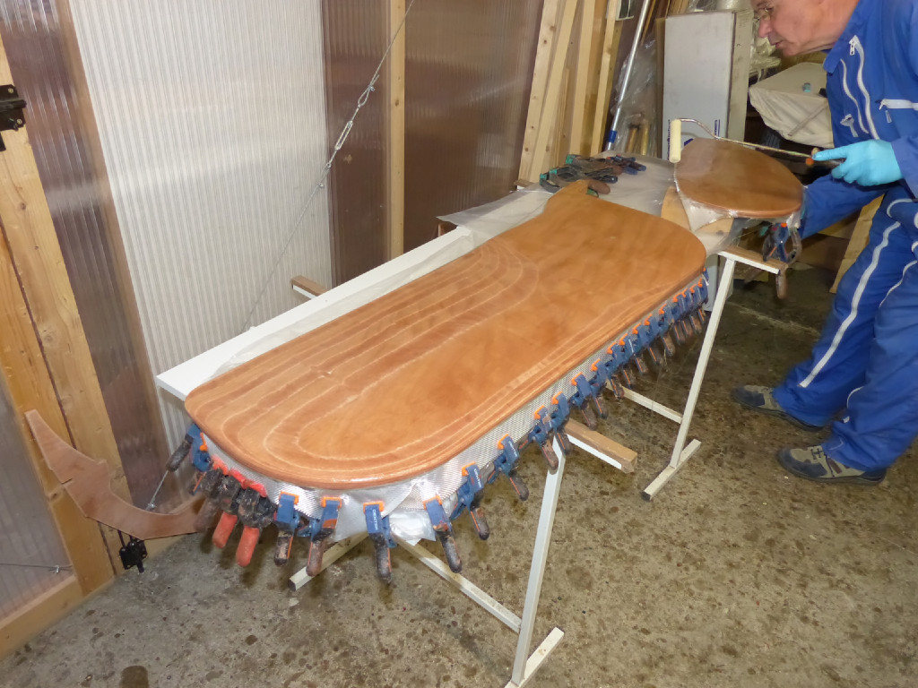 Nous stratifions successivement les deux faces de la dérive et du safran. Les pinces accrochées au bord de la pièce de tissu lestent le bord et le forcent à épouser la courbure en ogive du bord d'attaque? Nous n'en avons pas mis sur le bord de fuite : le tissu reste parallèle à la surface peincipale et sera coupé au droit du bord de fuite. 