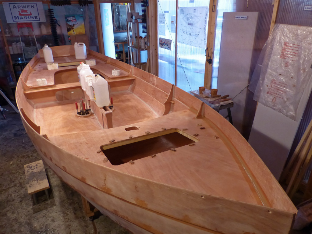 Collage des pontages avant et arrière et du chapeau du puits de dérive. On voit à l'avant que nous n'avons pas lesté le pontage, il tient tou seul en place car il est inséré en force entre les bordés. Notez que les vis temporaires qui pressent le collage de l'endrement des trappes sont encore en place. Nous avons fait les trous de ces vis aux emplacements des vis définitives des deux trappes et pourrons ainsi les réutiliser sans en faire de nouveaux et devoir boucher les anciens. On voit bien au premier plan à droite le gros joint-congé de collage et d'étanchéité du pontage avant. 