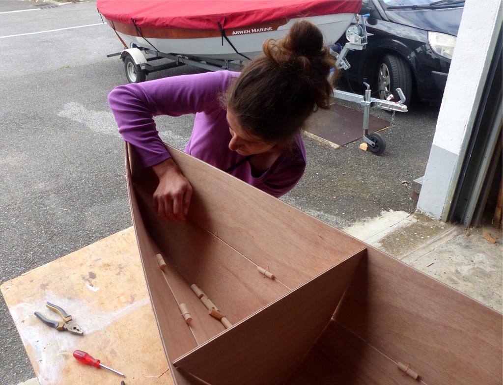 Guenola est venue m'aider pour la couture de la coque afin de se faire la main en vue de la construction d'un Goat Island Skiff (&agrave; suivre !) Nous cousons les panneaux lat&eacute;raux afin de compl&eacute;ter la coque. Notez les petits bouts de rondin pris dans certaines sutures : leur r&ocirc;le est d'am&eacute;liorer l'alignement des panneaux sur les sutures. Comme sur le Mill Creek 13, tous les trous des sutures sont perc&eacute;s lors de la fabrication du kit, nous n'en ajouterons que quelques uns. 
