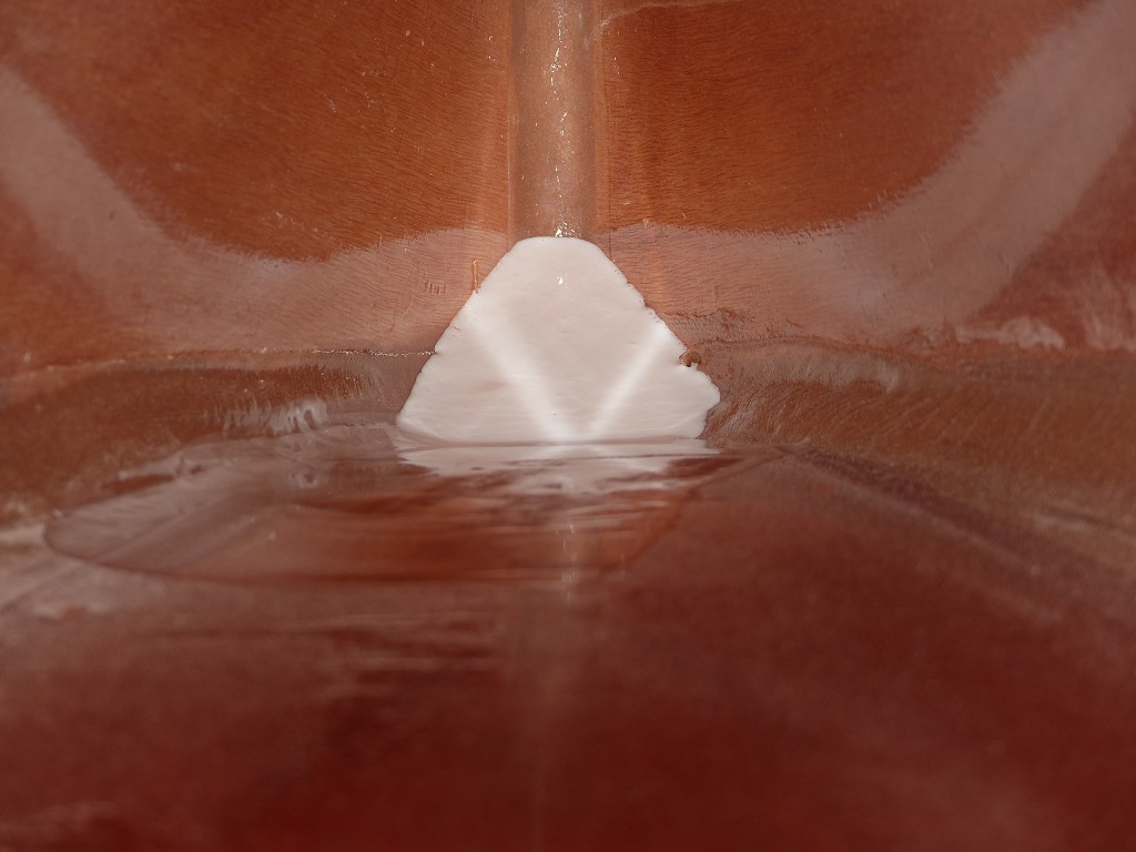 Cette vue de l'int&eacute;rieur de la pointe avant du Wood Duck 12 montre la surface de l'&eacute;poxy apr&egrave;s coulage (la couleur blanche vient des micro sph&egrave;res). J'ai utilis&eacute; ma raclette pour pousser ce qui restait sur le pont, car comme vous le savez d&eacute;j&agrave;, il y a 1.45 m entre l'avant de l'ouverture du cockpit et je n'ai pas le bras assez long pour aller verser dans le haut de l'&eacute;trave... Notez que les deux "ailes" blanches sont les reflets de la surface de la coul&eacute;e. 