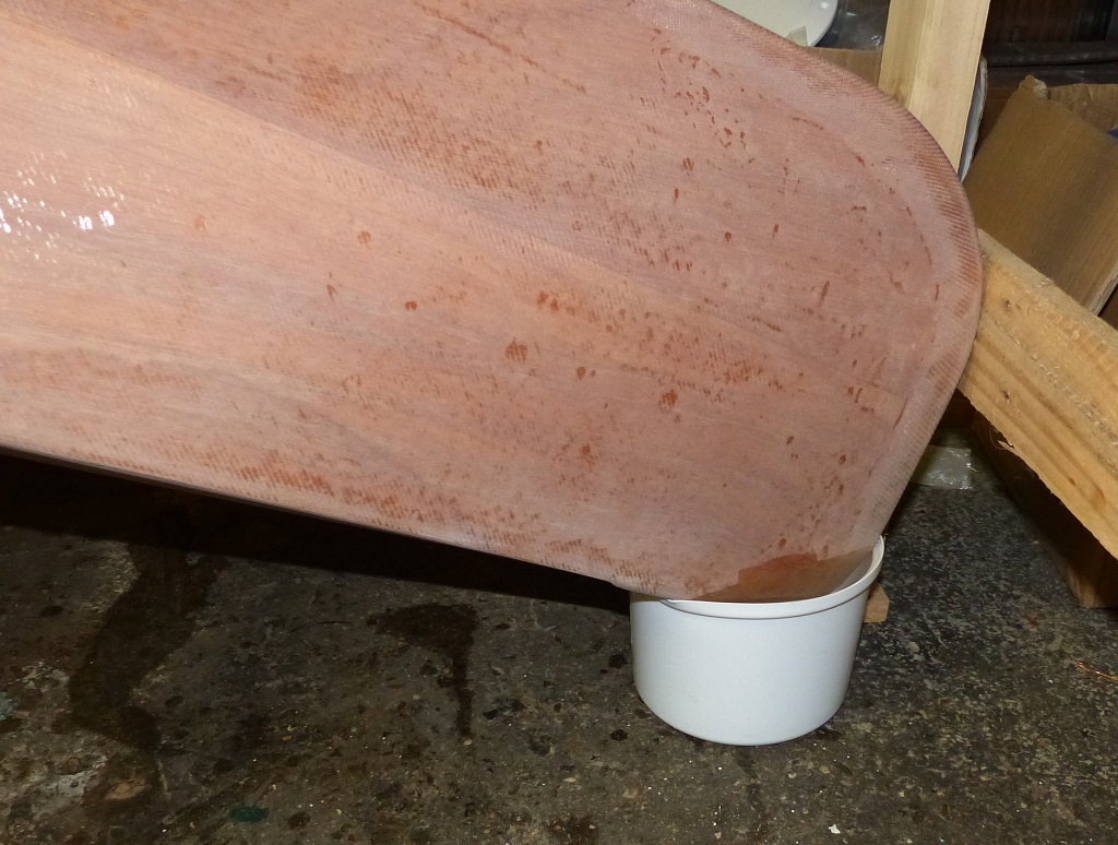 Il faut toujours donner bien abreuver son kayak... En fait, j'ai pos&eacute; l'avant dans ce petit seau d'eau afin de diffuser la chaleur qui va &ecirc;tre caus&eacute;e par la r&eacute;action de l'&eacute;poxy. En effet, le d&eacute;gagement de chaleur peut &ecirc;tre assez intense et il pourrait blanchir la stratification ext&eacute;rieure du kayak si on ne prenait pas cette pr&eacute;caution. Je reste un peu partag&eacute; sur le coulage de ces blocs car je n'aime pas ajouter du poids dans les extr&eacute;mit&eacute;s du kayak. En effet, ajouter du poids dans l'absolu est nuisible, et encore plus s'il est dans les extr&eacute;mit&eacute;s car cela perturbe l'&eacute;quilibre du kayak en dispersant le poids. Mais il ne s'agit que de 400 grammes sur un poids total (&agrave; v&eacute;rifier) de 18100 grammes, et je pense que leur utilit&eacute; justifie de les ajouter. 