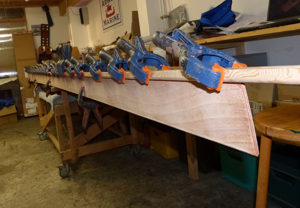 En parall&egrave;le du d&eacute;but de la couture, je colle les serres bauqui&egrave;res sur le bord haut des panneaux lat&eacute;raux. Notez que j'ai pass&eacute; un coup de d&eacute;fonceuse avec une fraise en quart de rond sur l'ar&ecirc;te inf&eacute;rieure ext&eacute;rieure de la serre qui restera expos&eacute;e. 