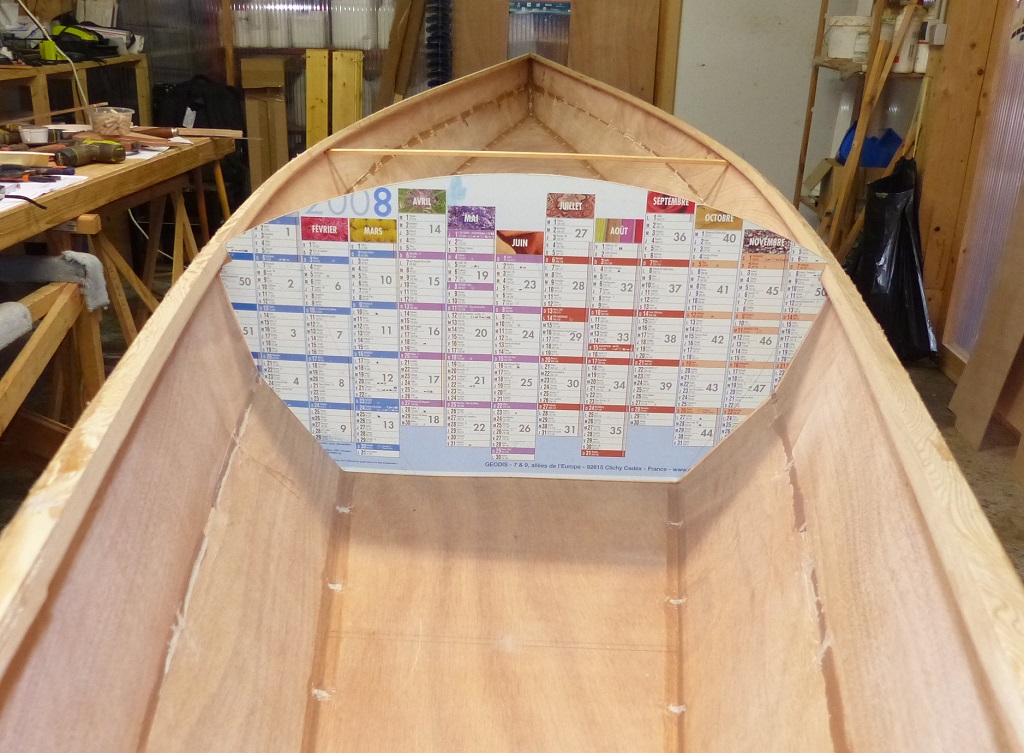 Vue du c&ocirc;t&eacute; du caisson avant : on voit le trac&eacute; double de la cloison originale au premier plan. Ce d&eacute;placement r&eacute;duit la longueur du cockpit, et donc la longueur disponible aux pieds pour la place avant. Les cale-pieds avant se trouvent normalement 10 cm en avant de cette cloison, il faudra donc que le plus grand des deux pagayeurs se place &agrave; l'arri&egrave;re, ce qui est de toute fa&ccedil;on l'habitude. Je suis fort aise d'avoir conserv&eacute;, puis surtout retrouv&eacute; au moment o&ugrave; j'en avais besoin, de calendrier mural de 2008 ! 