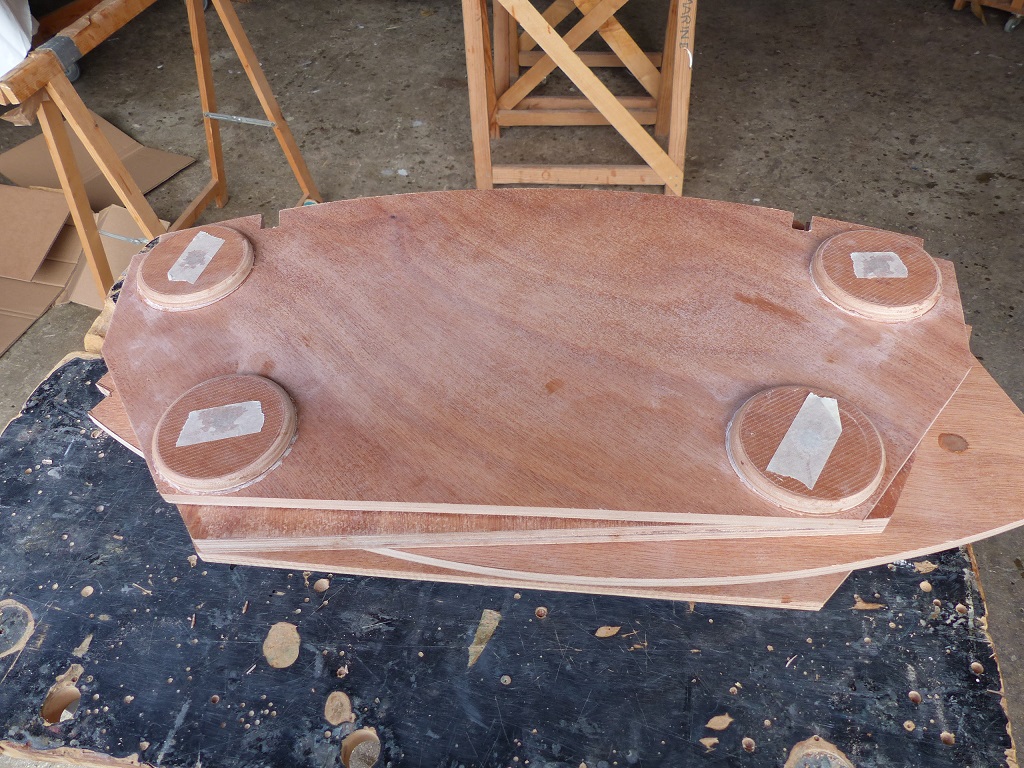 J'ai coup&eacute; mes doubles cloisons dans du contreplaqu&eacute; de 9 mm que j'avais pr&eacute;alablement stratifi&eacute; pour durcir sa surface et j'ai ajout&eacute; aux emplacements des boulons-&eacute;crous d'assemblage des rondelles de 84 mm de diam&egrave;tre d&eacute;coup&eacute;es &agrave; la scie-cloche dans le m&ecirc;me contreplaqu&eacute; stratifi&eacute;. La stratification vise &agrave; durcir la surface et r&eacute;duire le risque de prise de jeu par compression du contreplaqu&eacute;. Les bouts de bande adh&eacute;sive servent &agrave; obturer un c&ocirc;t&eacute; afin de couler de l'&eacute;poxy l&eacute;g&egrave;rement charg&eacute;e pour remplir les trous de 12 mm que j'ai perc&eacute;s &agrave; l'emplacement des boulons-&eacute;crous d'assemblage. Je repercerai ensuite ces trous en 8 mm pour les boulons, de fa&ccedil;on &agrave; laisser un "tube" d'&eacute;poxy qui prot&egrave;gera la tranche du contreplaqu&eacute;. 