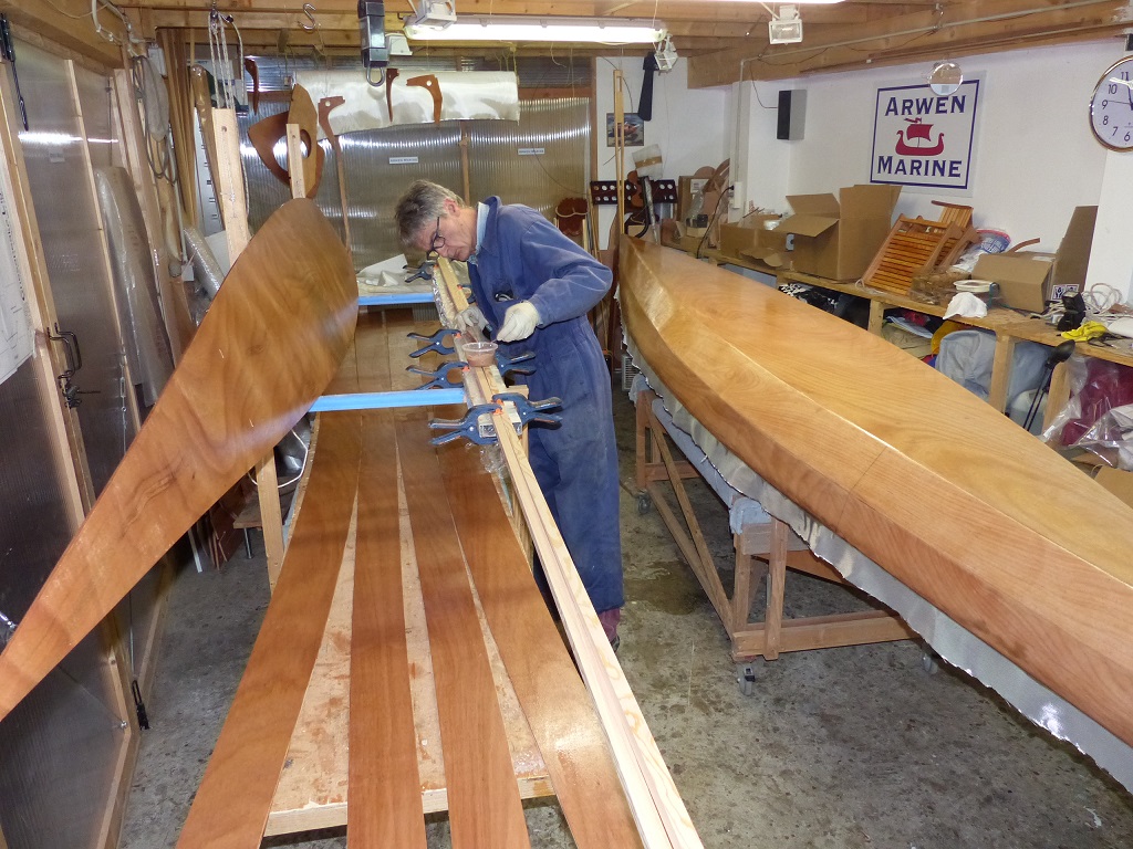 Pierre pr&eacute;pare le collage des scarfs des serres bauqui&egrave;res (pas de joint-puzzle dans les bouts de bois massif !) apr&egrave;s avoir pass&eacute; la couche d'impr&eacute;gnation &eacute;poxy sur les panneaux de coque. On voit derri&egrave;re lui que nous avons aussi satur&eacute; le tissu de verre sur le premier Mill Creek. 