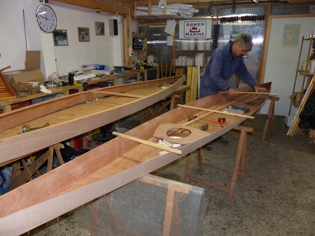 Les deux panneaux lat&eacute;raux sont cousus aux ext&eacute;mit&eacute;s et une barre d'ouverture donne leur &eacute;cartement au bau maximum. Nous allons les poser sur la sole &agrave; laquelle ont &eacute;t&eacute; cousus les deux panneaux de bouchain. Pierre dispose des bouts de tasseau en travers afin d'&eacute;viter qu'ils ne passent &agrave; travers, en attendant que les sutures les tiennent en place. 