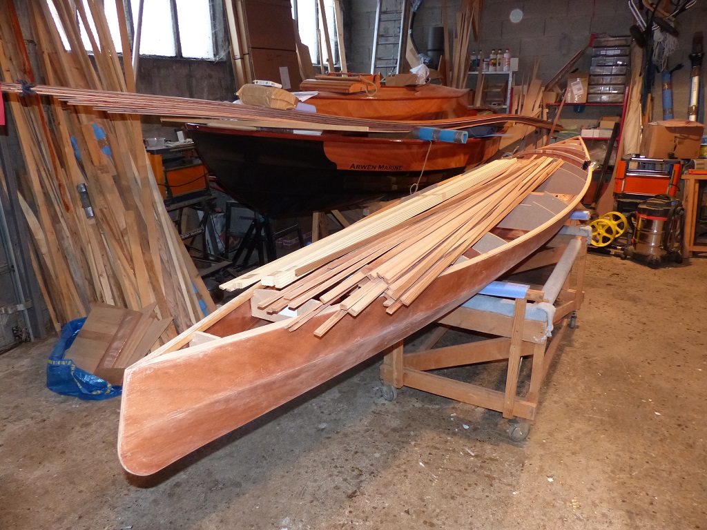 La sole et les bord&eacute;s du Wherry Tandem sont pos&eacute;s sur le Skerry sur le c&ocirc;t&eacute; du Mill Creek 13 (dans lequel je dois encore installer le si&egrave;ge et les cale-pieds, puis que je dois encore poncer, vernir et peindre, presque rien &agrave; faire). Ce sont les lattes que nous allons utiliser avec Pierre pour construire le pont de son Mill Creek 16.5 qui sont pos&eacute;es dessus. 