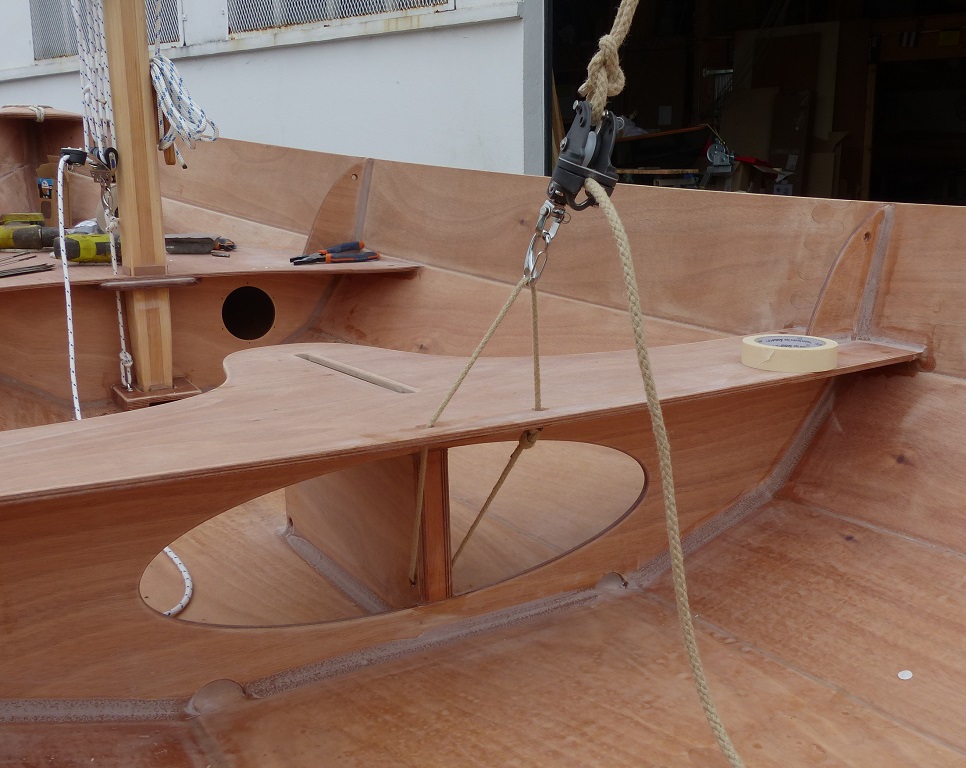 Gros plan sur le capelage de l'&eacute;coute : une patte d'oie fix&eacute;e &agrave; travers la "jambe" arri&egrave;re du puits de d&eacute;rive et passant &agrave; travers le bord arri&egrave;re du si&egrave;ge central. La patte d'oie de la photo est un peu longue : elle devra &ecirc;tre gr&eacute;&eacute;e plus courte pour limiter le ballant de la poulie basse qui porte le coinceur de l'&eacute;coute. 