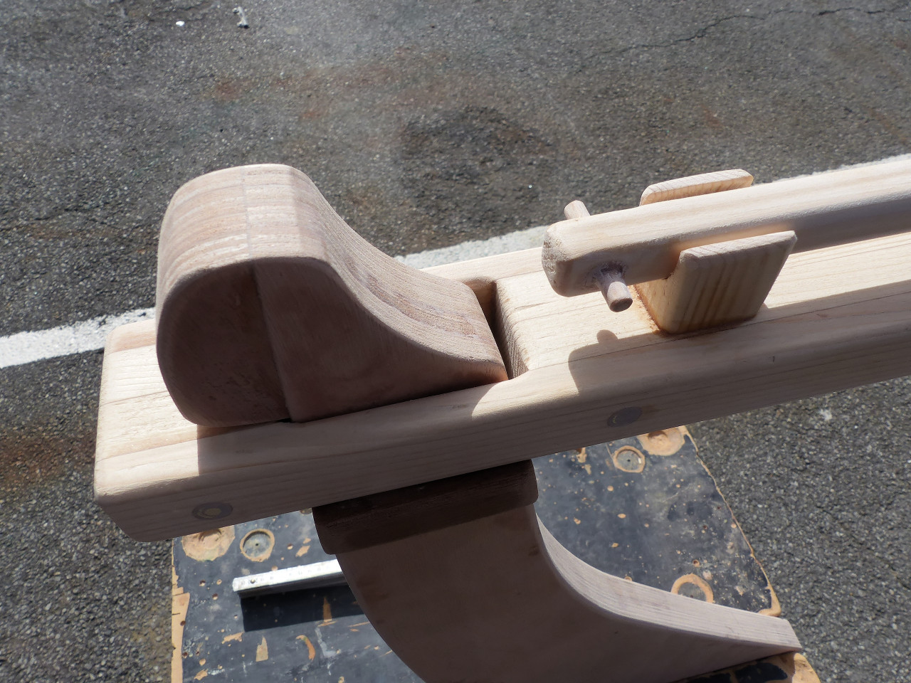 On voit que cette barre est cal&eacute;e verticalement par "l'occiput" ajout&eacute; au dos de la t&ecirc;te de gouvernail (viss&eacute;-coll&eacute; en place) et par deux chutes de liston en sapelli coll&eacute;es sur les c&ocirc;t&eacute;s de la t&ecirc;te de gouvernail, sous la barre. L'occiput emp&ecirc;che la barre de se lib&eacute;rer par le haut et les bouts de sapelli l'emp&ecirc;chent de partir par le bas. 